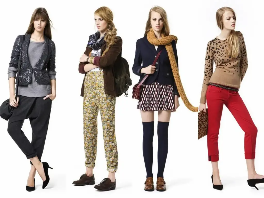 Four women are standing in a row, each showcasing a different outfit. From left to right: a blazer with joggers, floral-print pants with a backpack, a navy jacket with a mini skirt and knee-high socks, and red pants with a leopard print sweater. All wear stylish sh